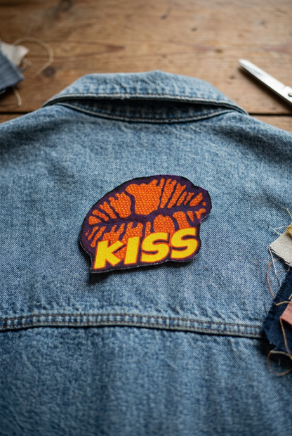 KISS strygemærke med læbemotiv placeret på ryggen af en vintage denimjakke