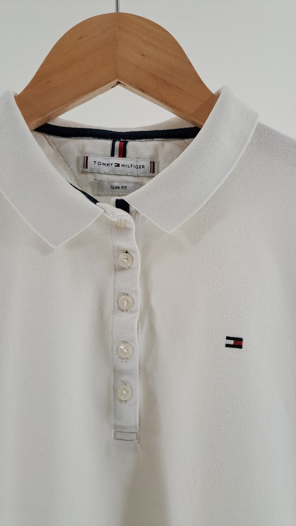 Nærbillede af polokrave, knapstolpe og broderet Tommy Hilfiger flaglogo på brystet