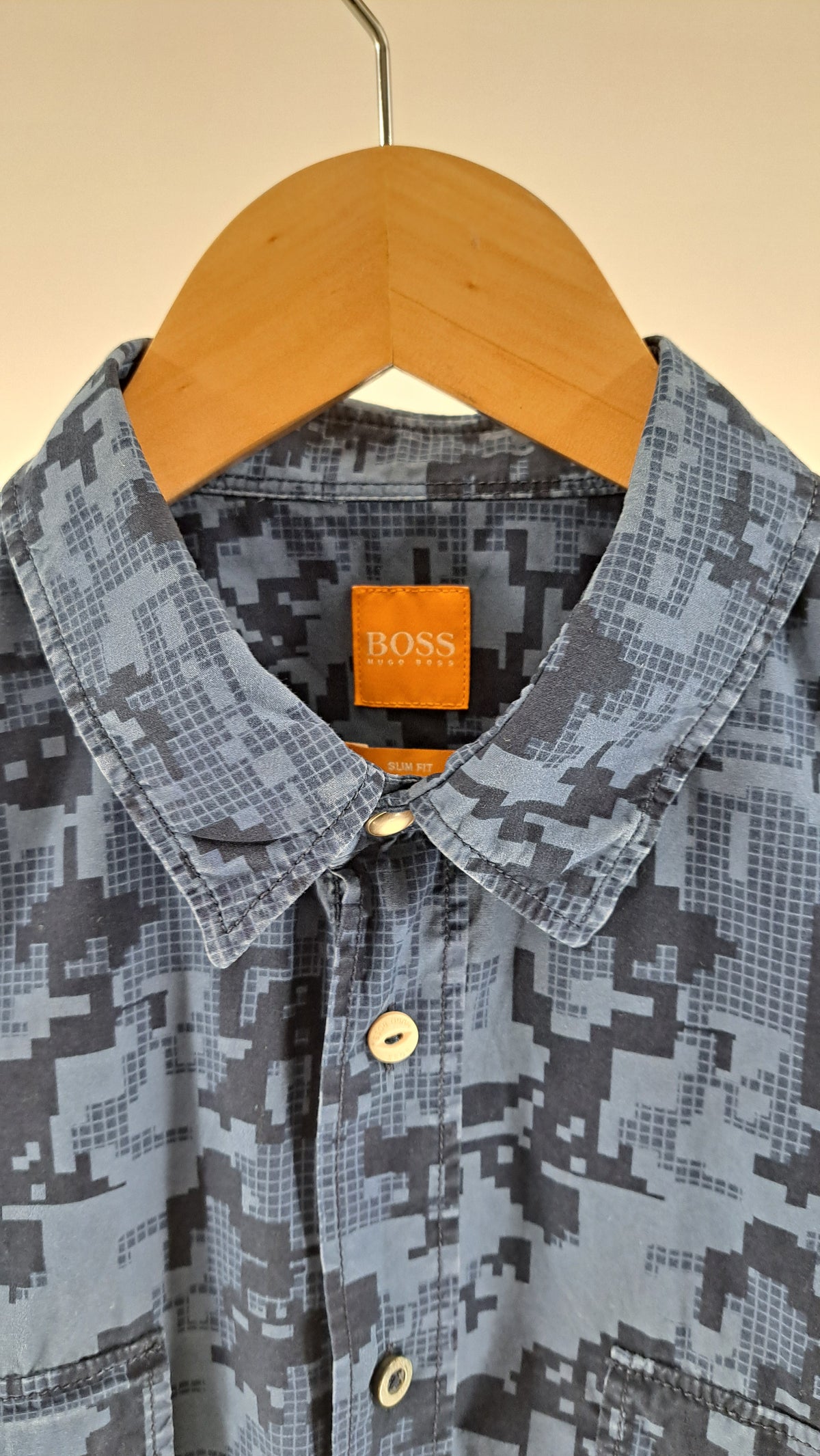 Nærbillede af krave og orange BOSS mærkelabel på blå camouflageskjorte
