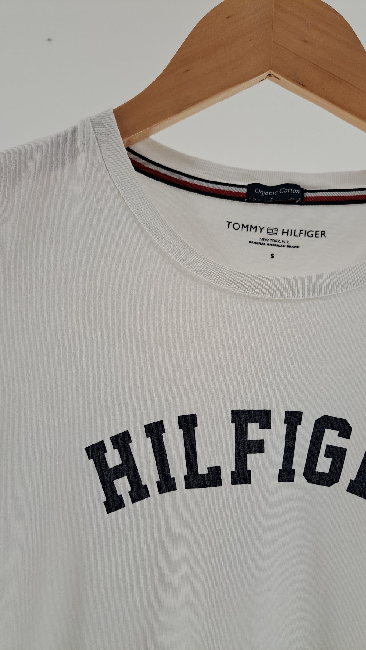 Nærbillede af rund halsudskæring og HILFIGER tekstprint på hvid T-shirt