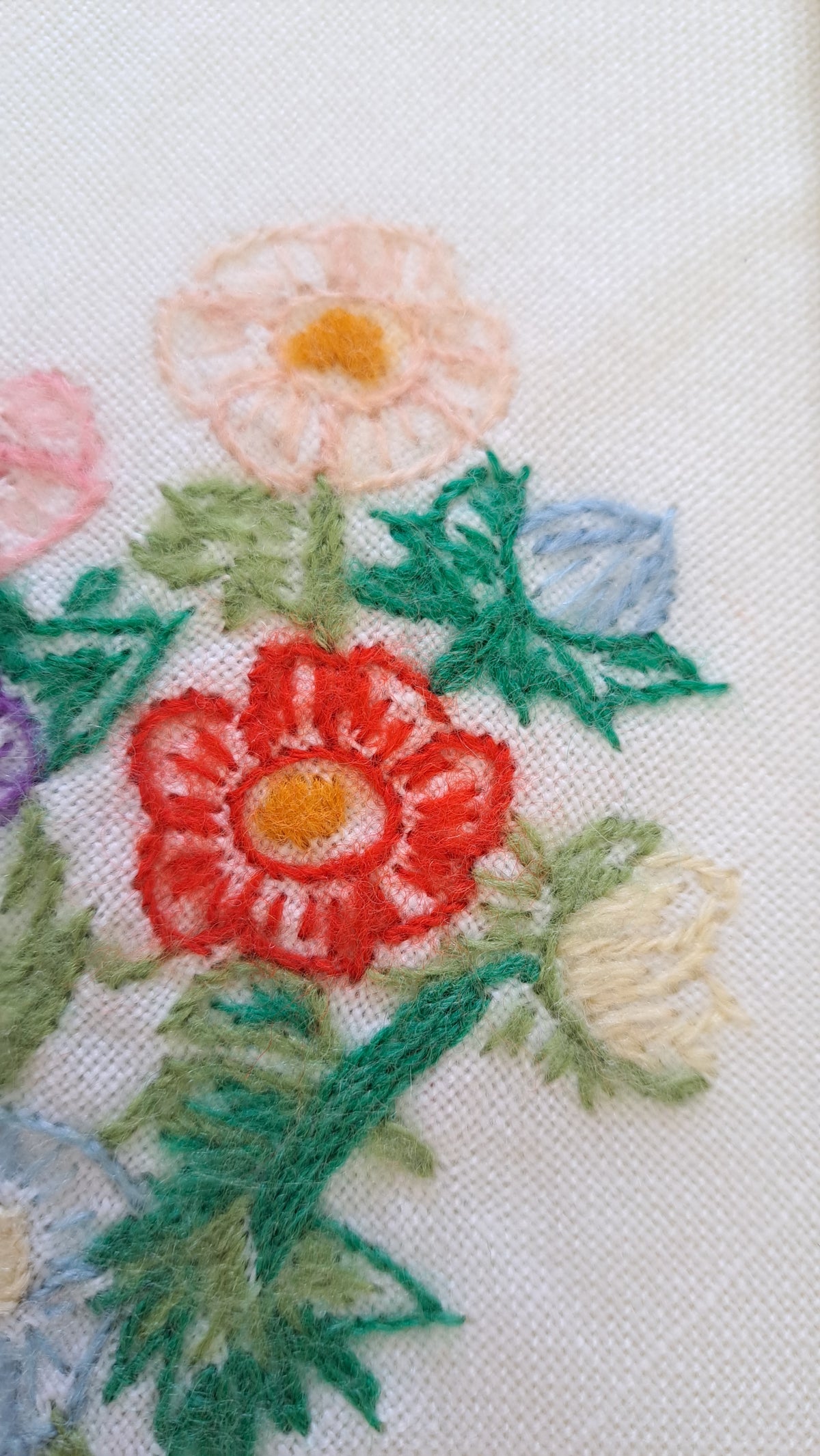 Nærbillede af detaljeret flerfarvet blomsterbroderi i røde, grønne og orange nuancer