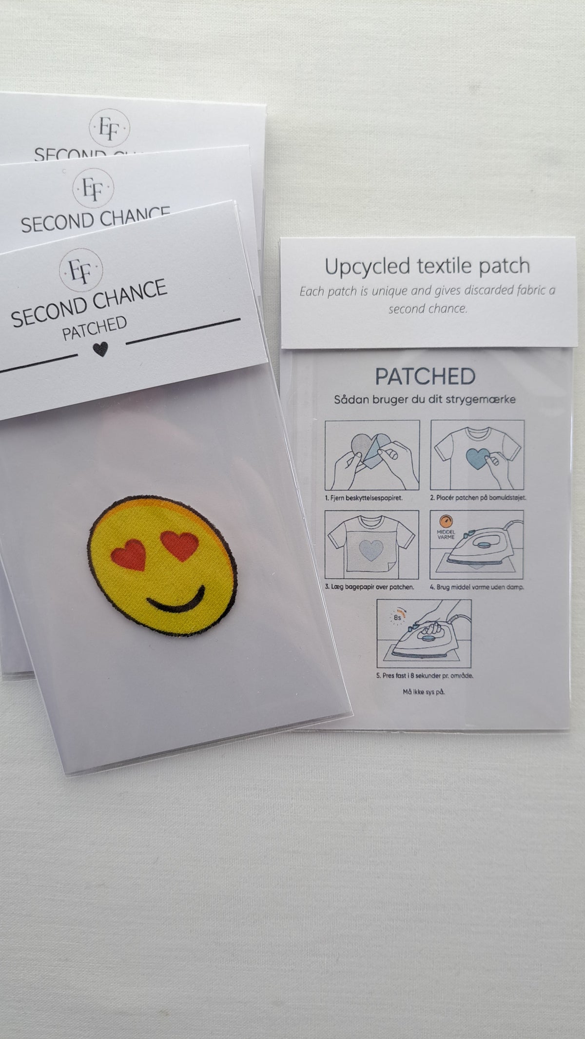 Gult Patched smiley-strygemærke med røde hjerteøjne i emballage ved siden af brugsvejledningen