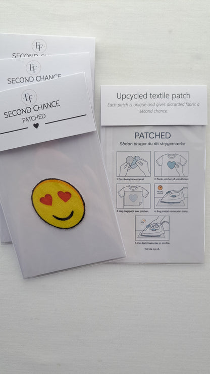 Gult Patched smiley-strygemærke med røde hjerteøjne i emballage ved siden af brugsvejledningen