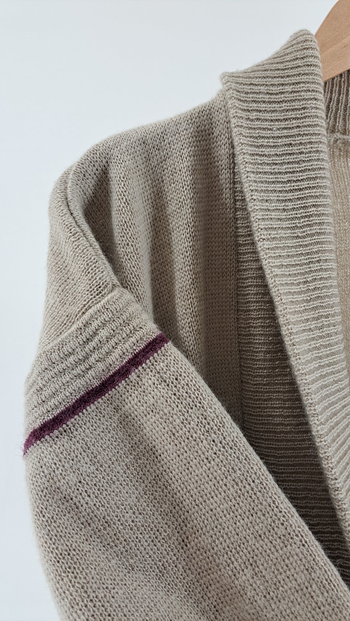 Nærbillede af ærme med mørk kontraststribe på beige uldcardigan