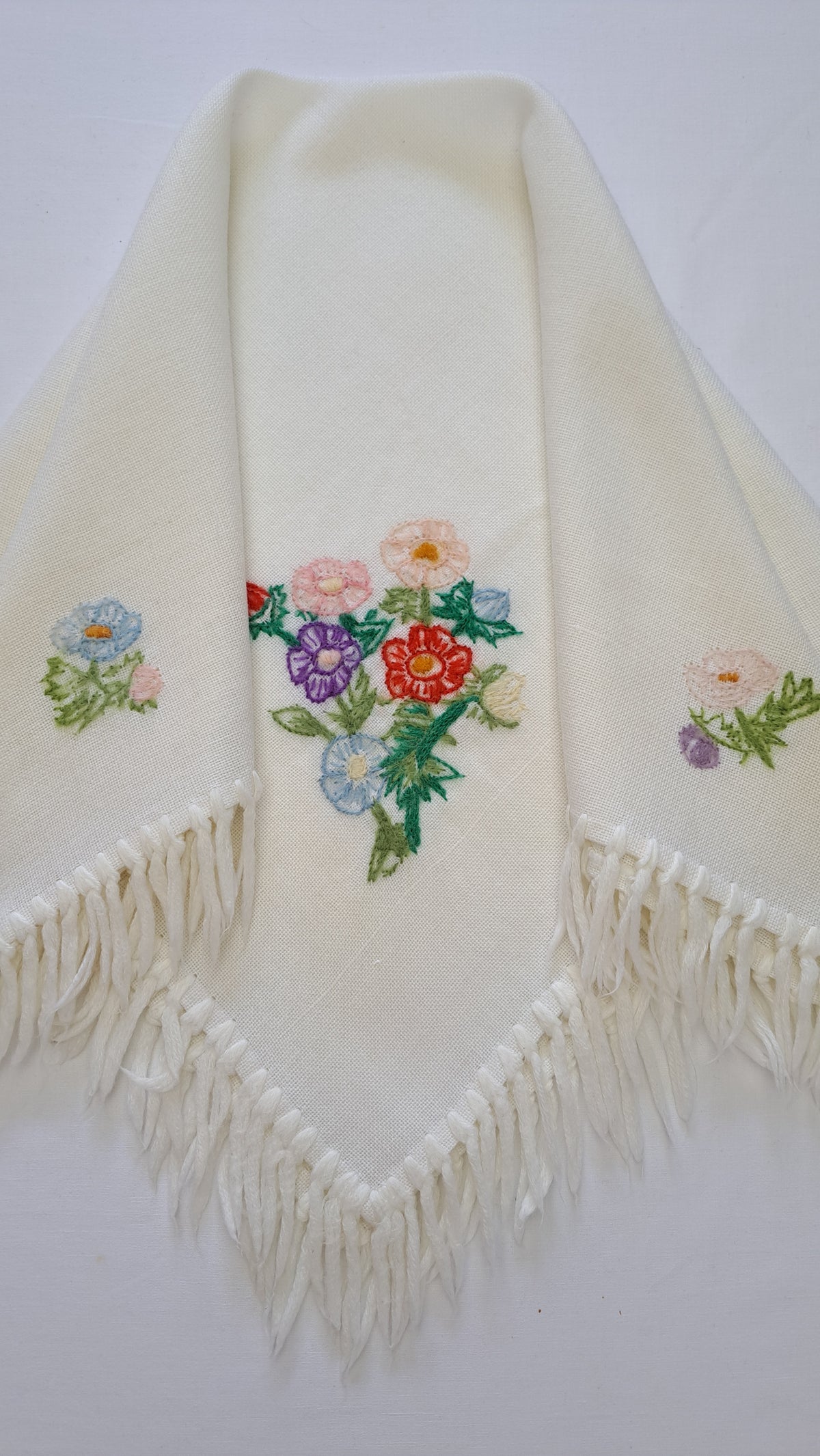 Cremefarvet vintage tørklæde med farverigt blomsterbroderi og frynser foldet i en spids