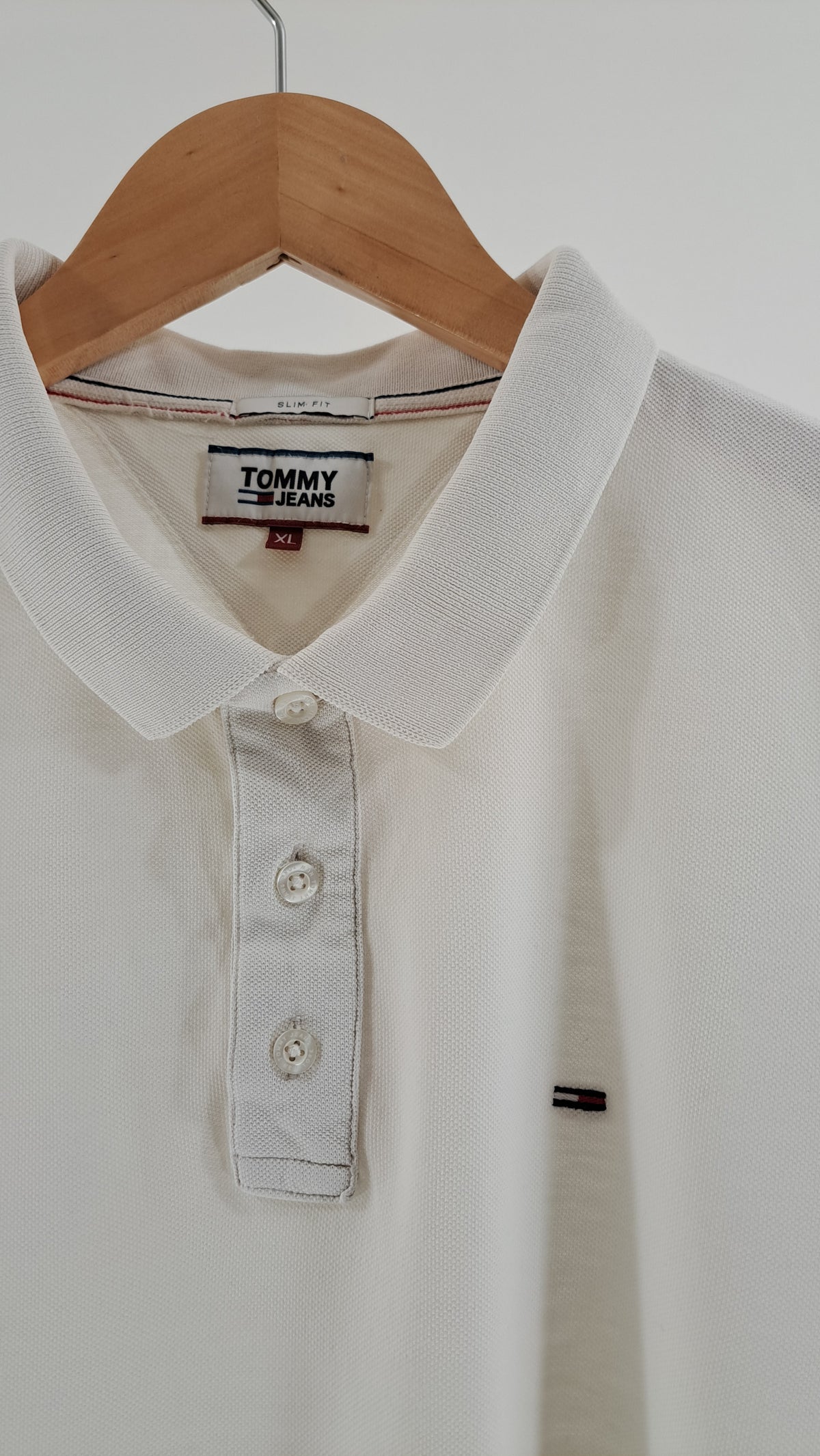 Nærbillede af polokrave med tre knapper og broderet Tommy Jeans flaglogo på brystet