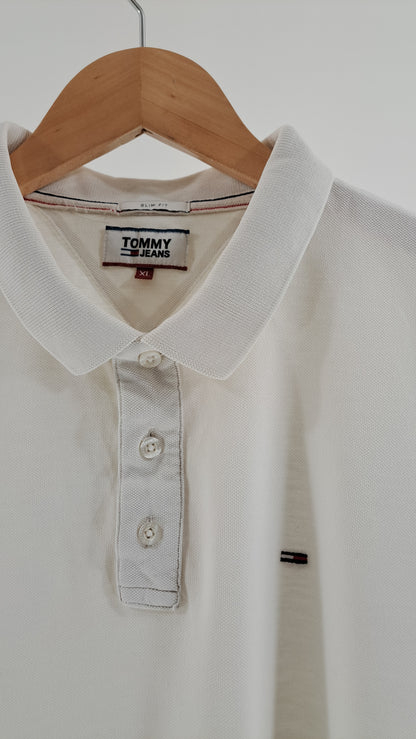 Nærbillede af polokrave med tre knapper og broderet Tommy Jeans flaglogo på brystet
