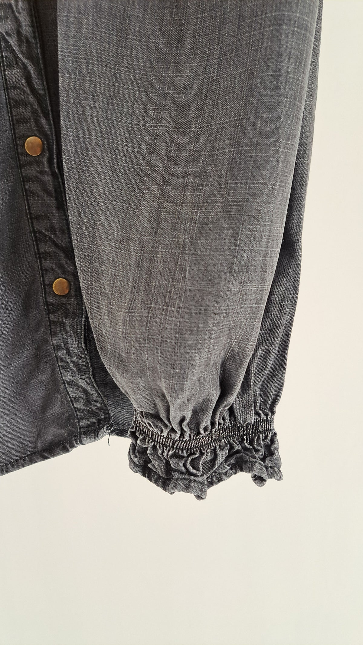 Nærbillede af ærme med elastisk smock ved håndleddet på denimskjorte