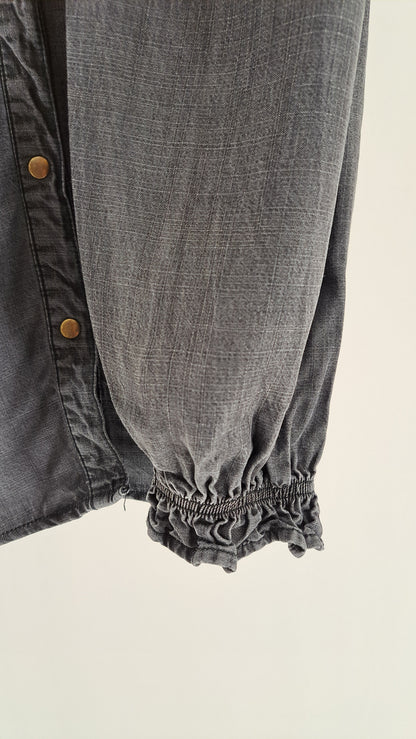 Nærbillede af ærme med elastisk smock ved håndleddet på denimskjorte
