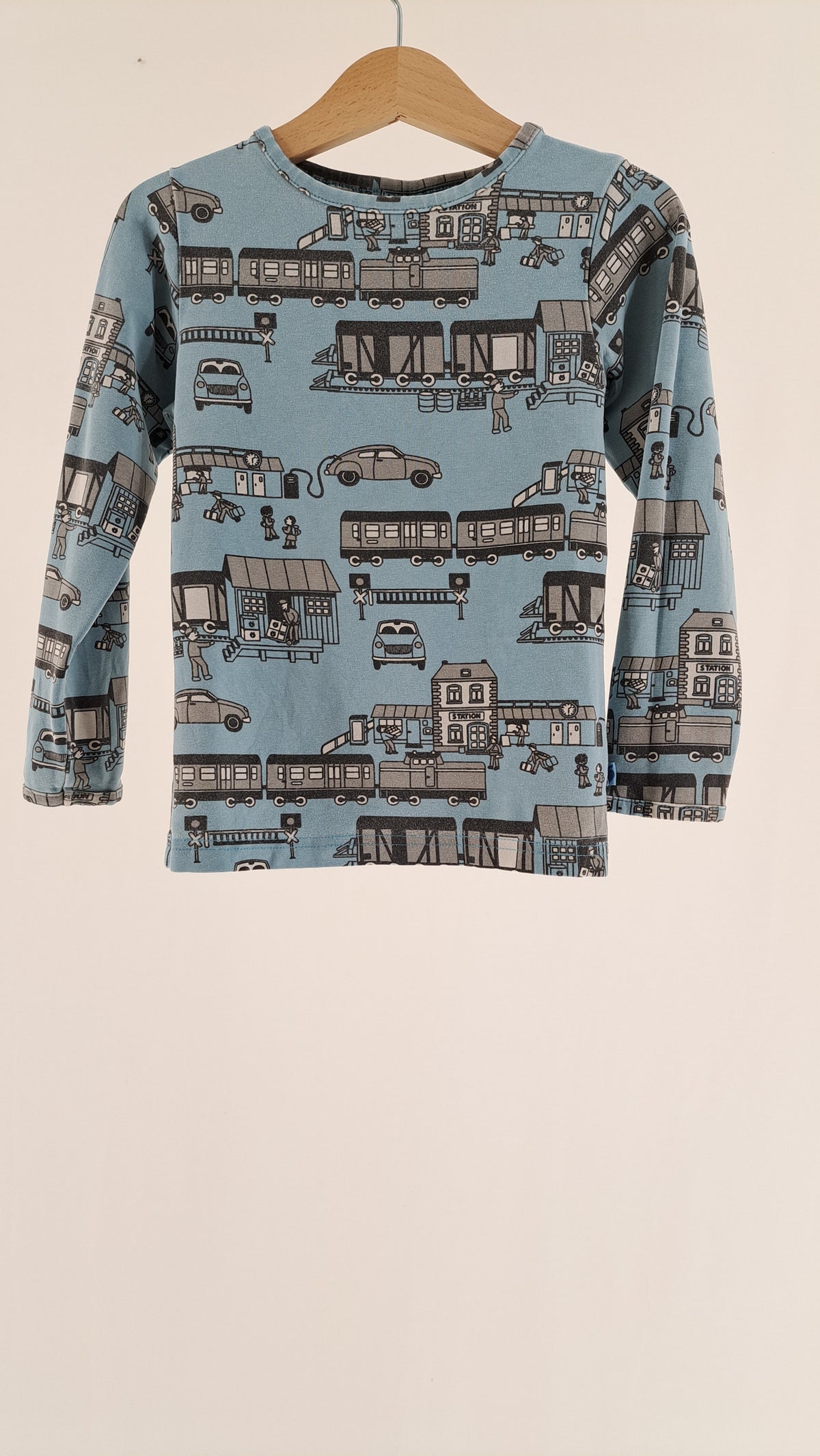 Lyseblå Småfolk langærmet børnebluse med print af tog, biler og bygninger set forfra