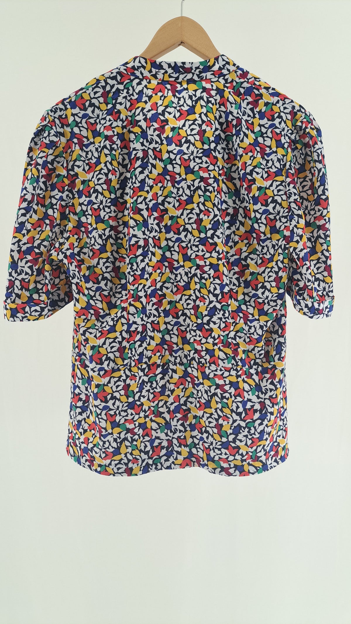 Nærbillede af knapdetalje på skulder af farverig vintage bluse