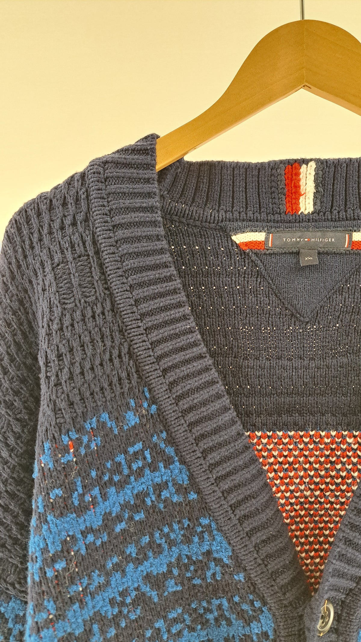 Nærbillede af V-udskæring, knaplukning og de grafiske striber på TOMMY HILFIGER cardigan