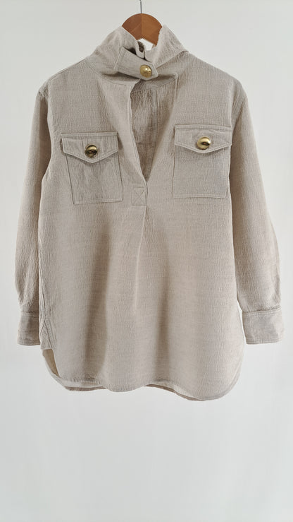 Lys beige By Malene Birger skjortekjole med guldknapper og brystlommer set forfra