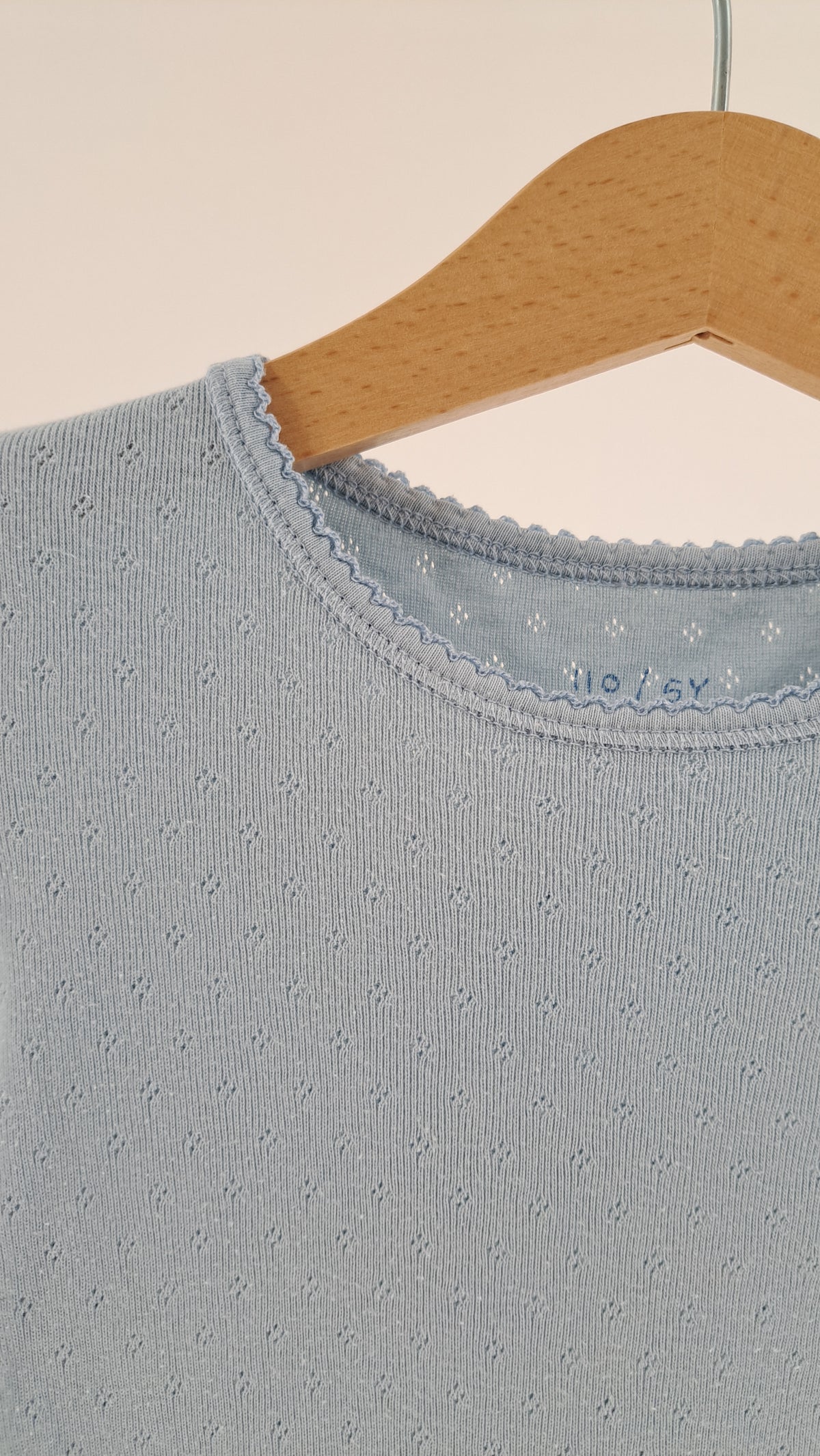 Nærbillede af halsudskæring og ribstruktur på lyseblå børne t-shirt