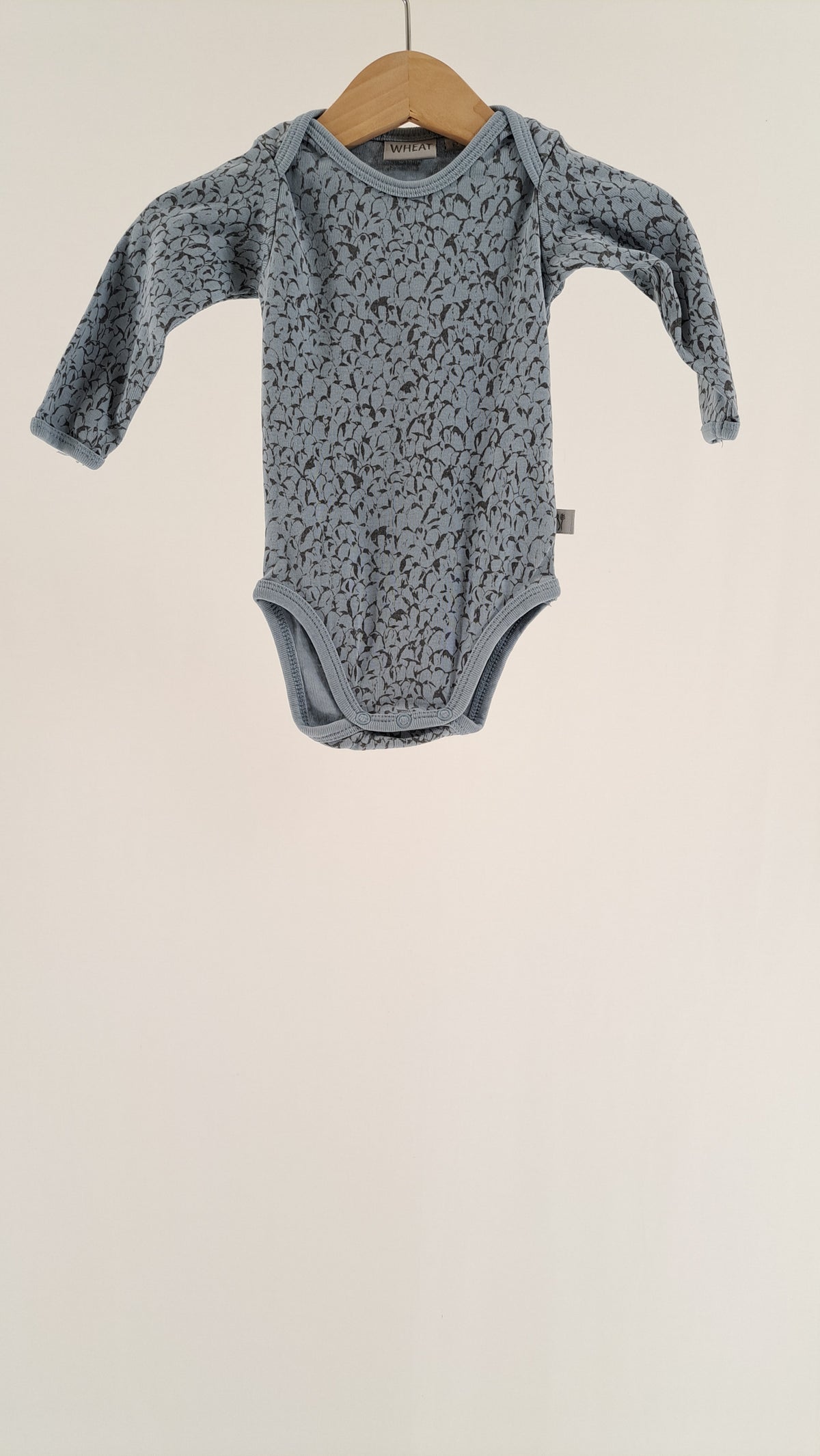 Lysblå langærmet Wheat babybody i str. 62 med blomsterprint set forfra