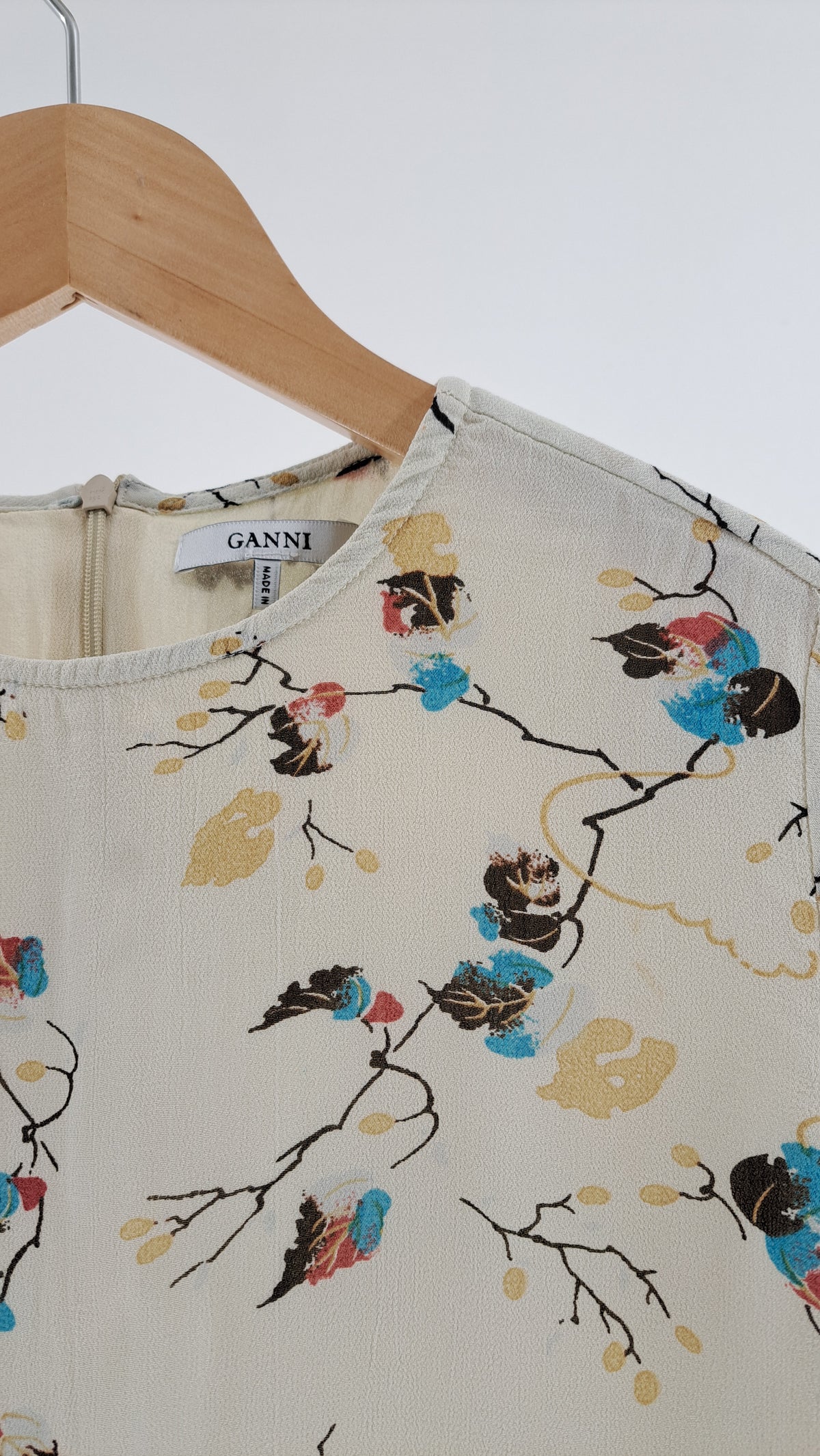 Nærbillede af rund halsudskæring og blomsterprint på cremefarvet GANNI bluse