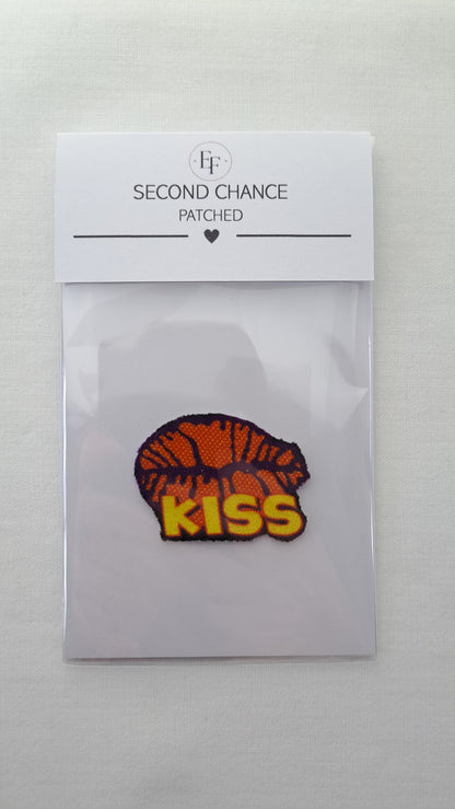 Nærbillede af Patched Lille KISS strygemærke i gennemsigtig Second Chance emballage